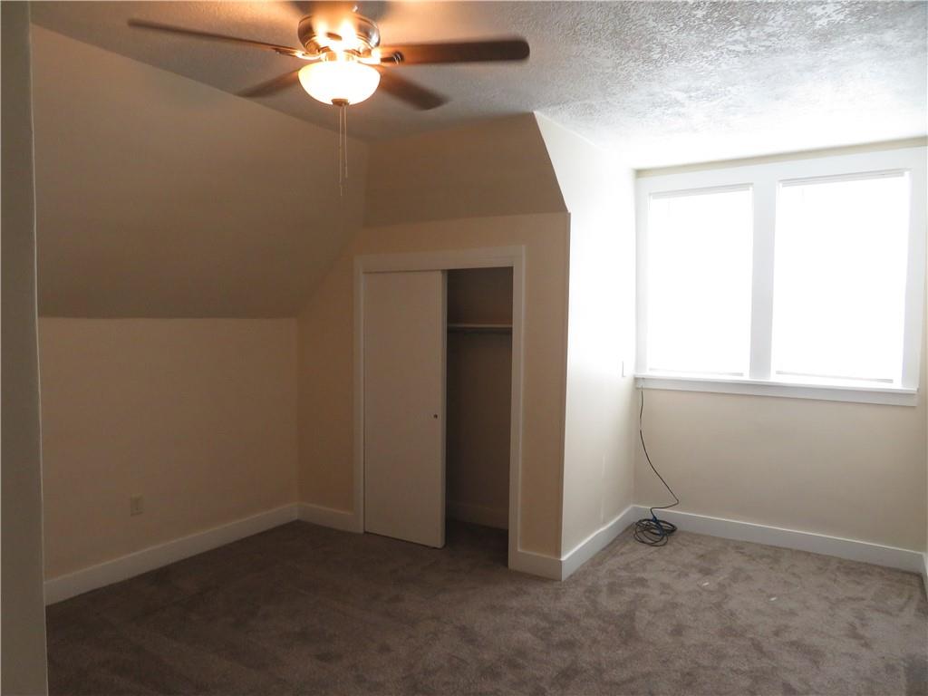 203 Main Street, Unit 3A Lyndora, PA 16045 - Photo 6 of 7 an empty room with a chandelier fan and windows