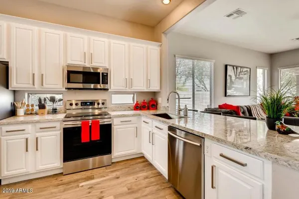a kitchen with stainless steel appliances granite countertop a sink dishwasher a stove and a refrigerator