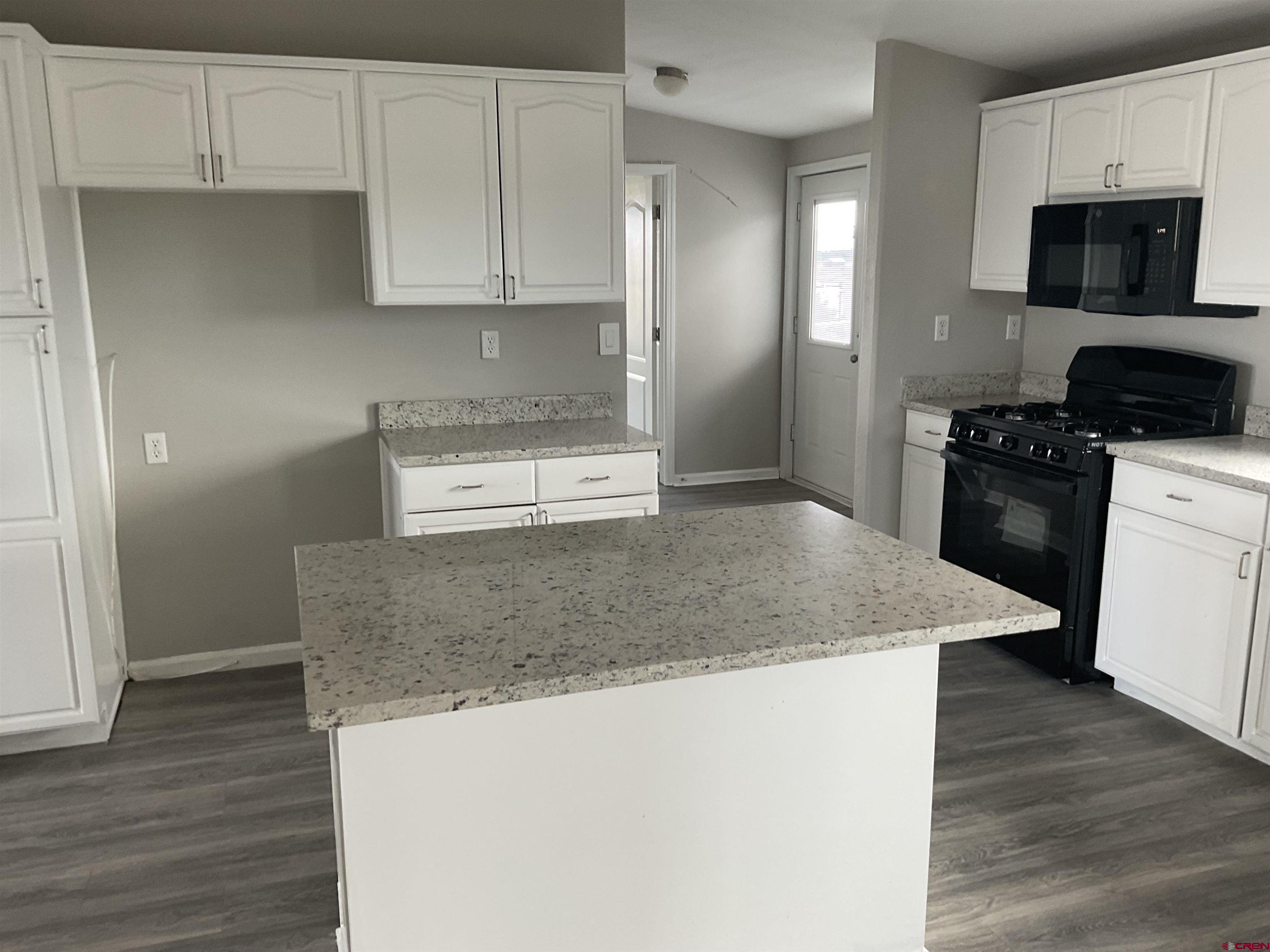 428 County Road 314 Ignacio, CO 81137 - Photo 18 of 24 a kitchen with granite countertop a refrigerator a stove top oven a sink and dishwasher with wooden floor