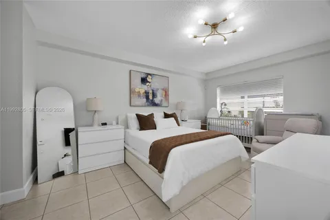 a large white bed sitting in a bedroom and chandelier