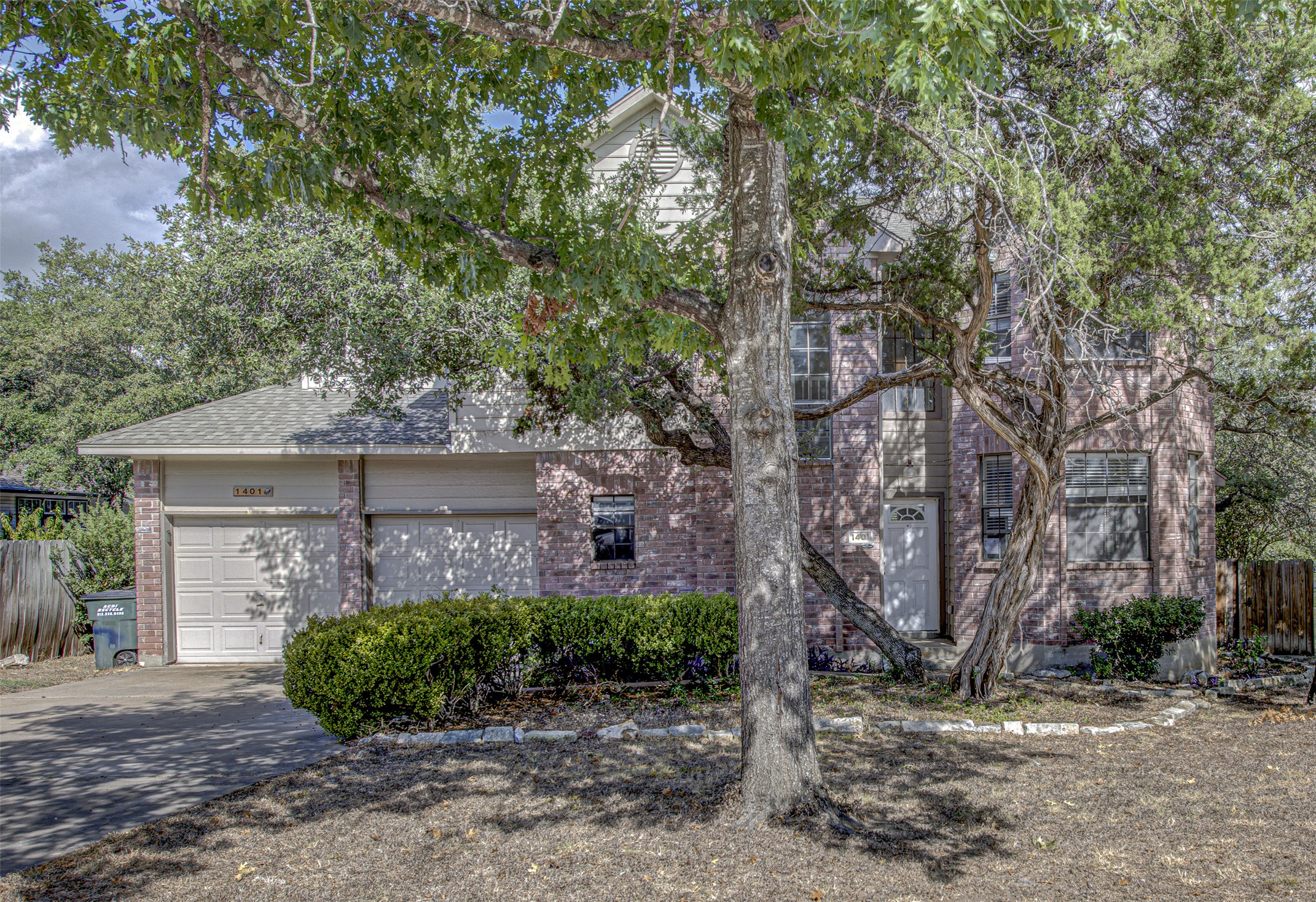 1401 Deepwoods Trail Leander, TX 78641 - Photo 1 of 1 View of property hidden behind natural elements with driveway, brick siding, a garage, and a shingled roof