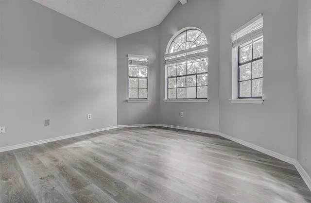 an empty room with wooden floor and windows