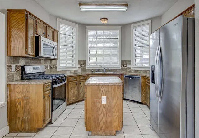 a kitchen with stainless steel appliances granite countertop a stove a sink and a refrigerator