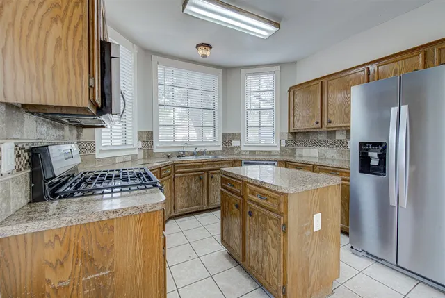 a kitchen with stainless steel appliances granite countertop a stove a sink dishwasher and a refrigerator