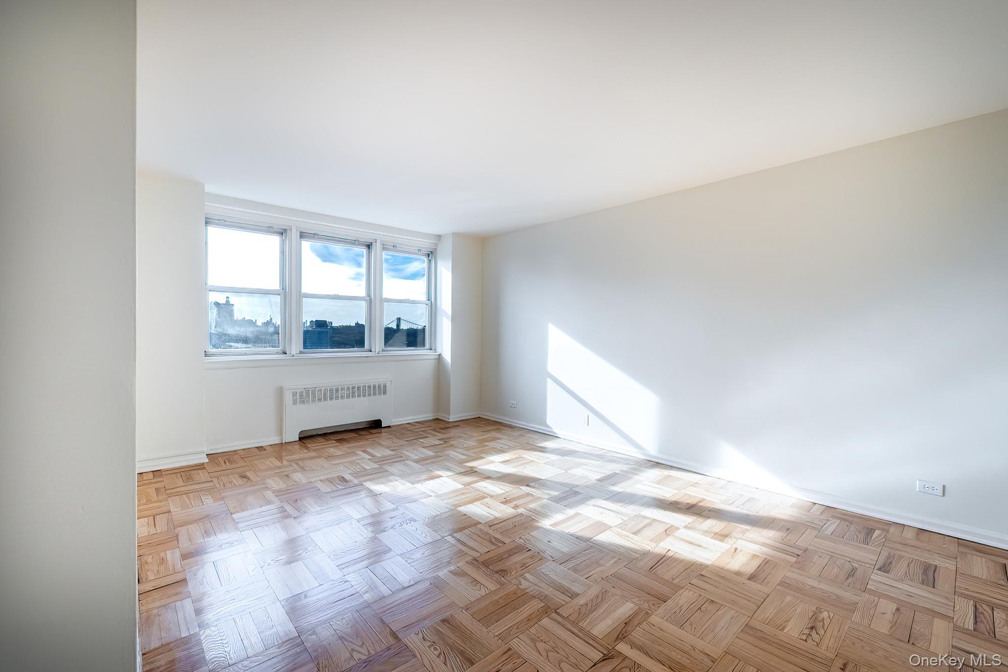 25 Knolls Crescent, Unit 8L Bronx, NY 10463 - Photo 4 of 21 Empty room featuring radiator heating unit and baseboards