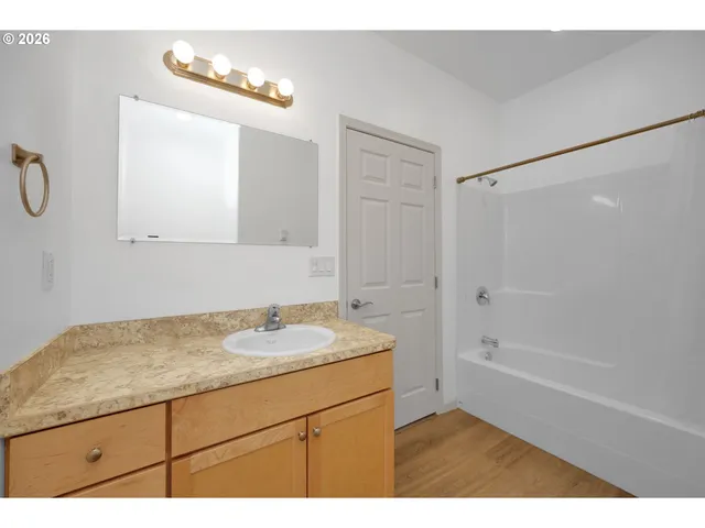 a bathroom with a granite countertop sink a mirror and a bathtub