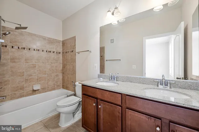 a bathroom with a granite countertop sink a toilet a mirror and shower