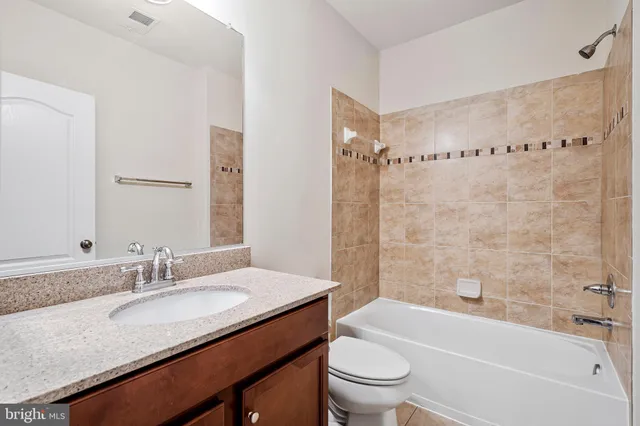 a bathroom with a granite countertop sink a toilet a mirror a bathtub and shower
