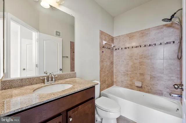 a bathroom with a granite countertop sink a toilet a mirror a bathtub and shower