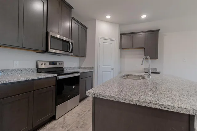 a kitchen with stainless steel appliances granite countertop a sink a stove and granite counter tops