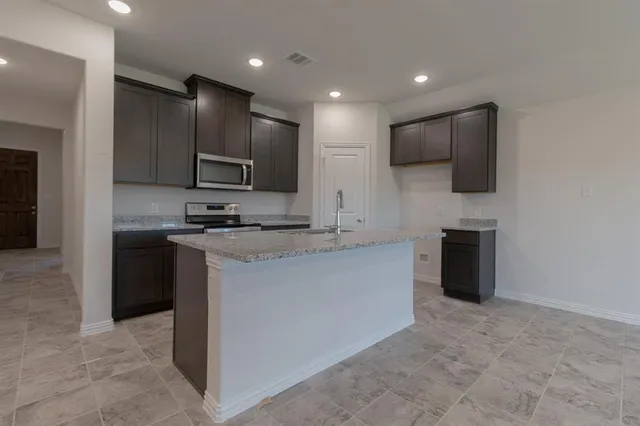 a kitchen with kitchen island a refrigerator and a stove top oven