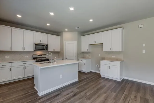 a kitchen with granite countertop a stove top oven sink and cabinets