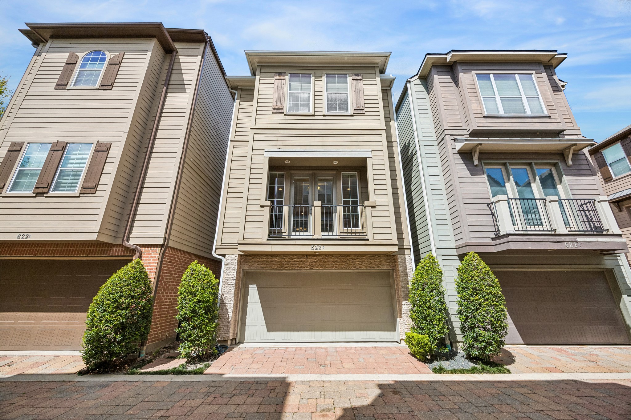 Charming three-story home with classic siding, shutters, and a private balcony. Gated community setting with attractive brick paver driveway and attached two-car garage. Well-maintained exterior with mature landscaping adds to the curb appeal.