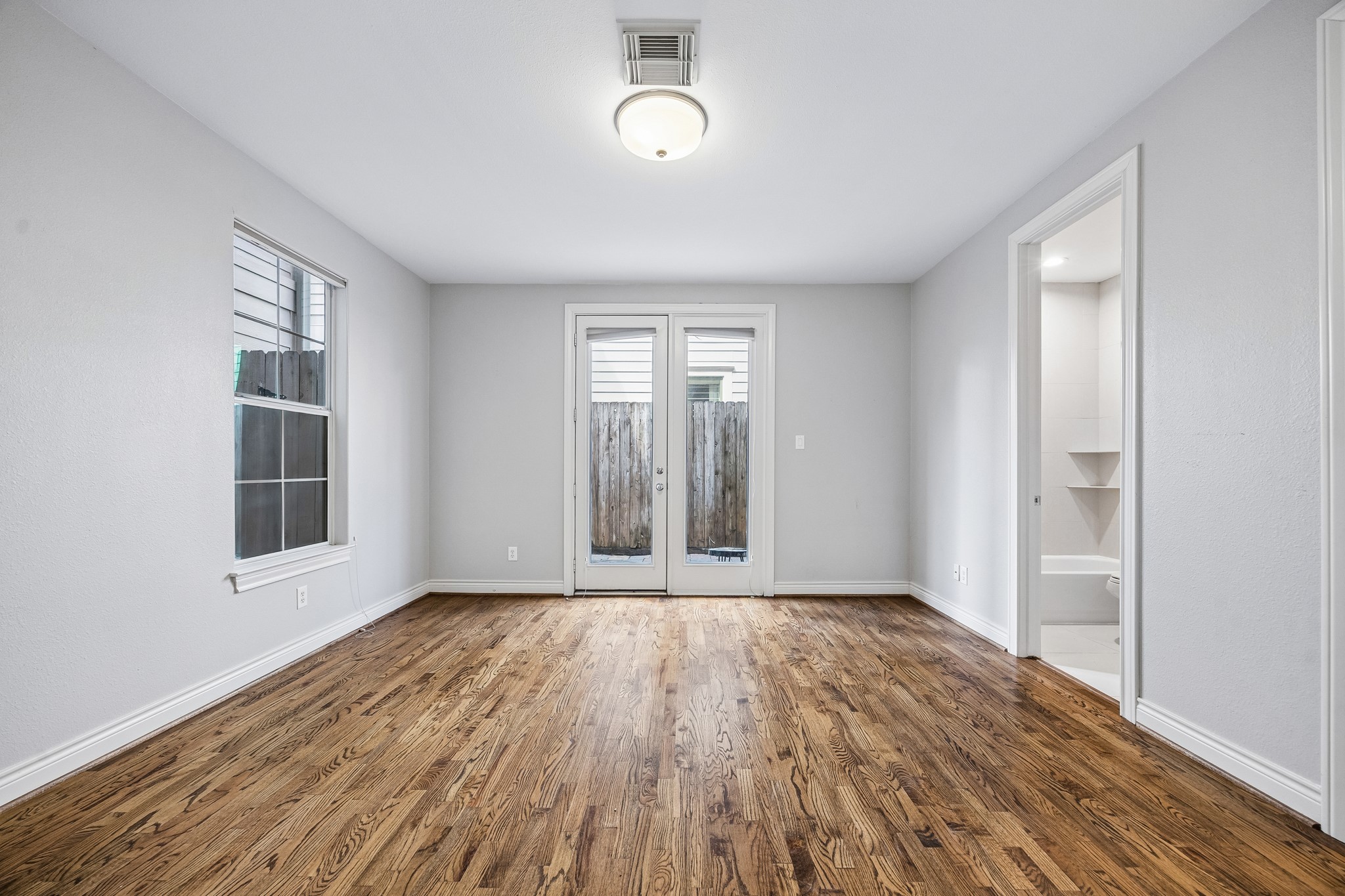 622 Rutland Street, Unit D Houston, TX 77007 - Photo 17 of 27 First floor bedroom with direct access to the backyard through French doors. Hardwood floors and natural light continue throughout. Convenient layout with en suite full bath.