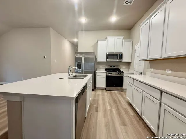 a kitchen with kitchen island a sink dishwasher stove and white cabinets