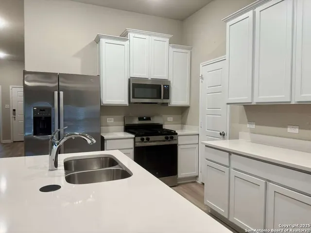 a kitchen with white cabinets and black appliances