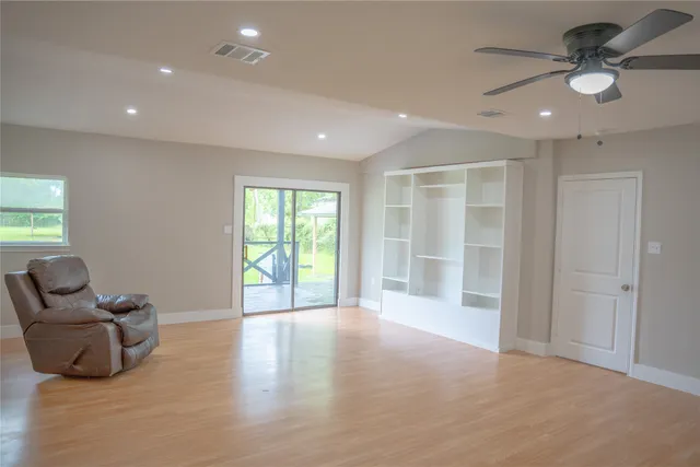 a view of an empty room with a window and kitchen view
