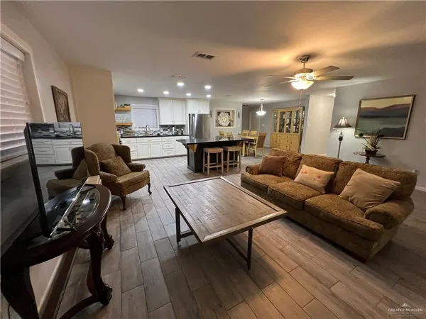 a living room with furniture a flat screen tv and kitchen view