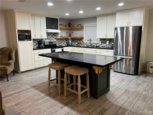a kitchen with stainless steel appliances granite countertop a table chairs sink refrigerator and microwave