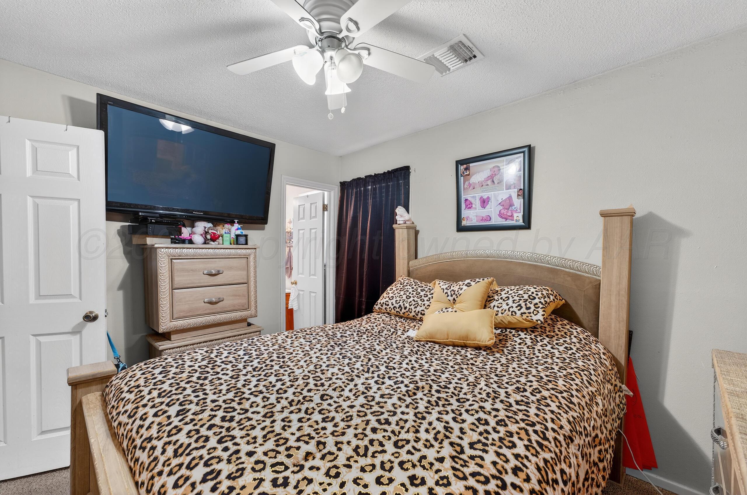 1007 Tudor Drive Amarillo, TX 79104 - Photo 14 of 27 a bedroom with a bed and a flat screen tv