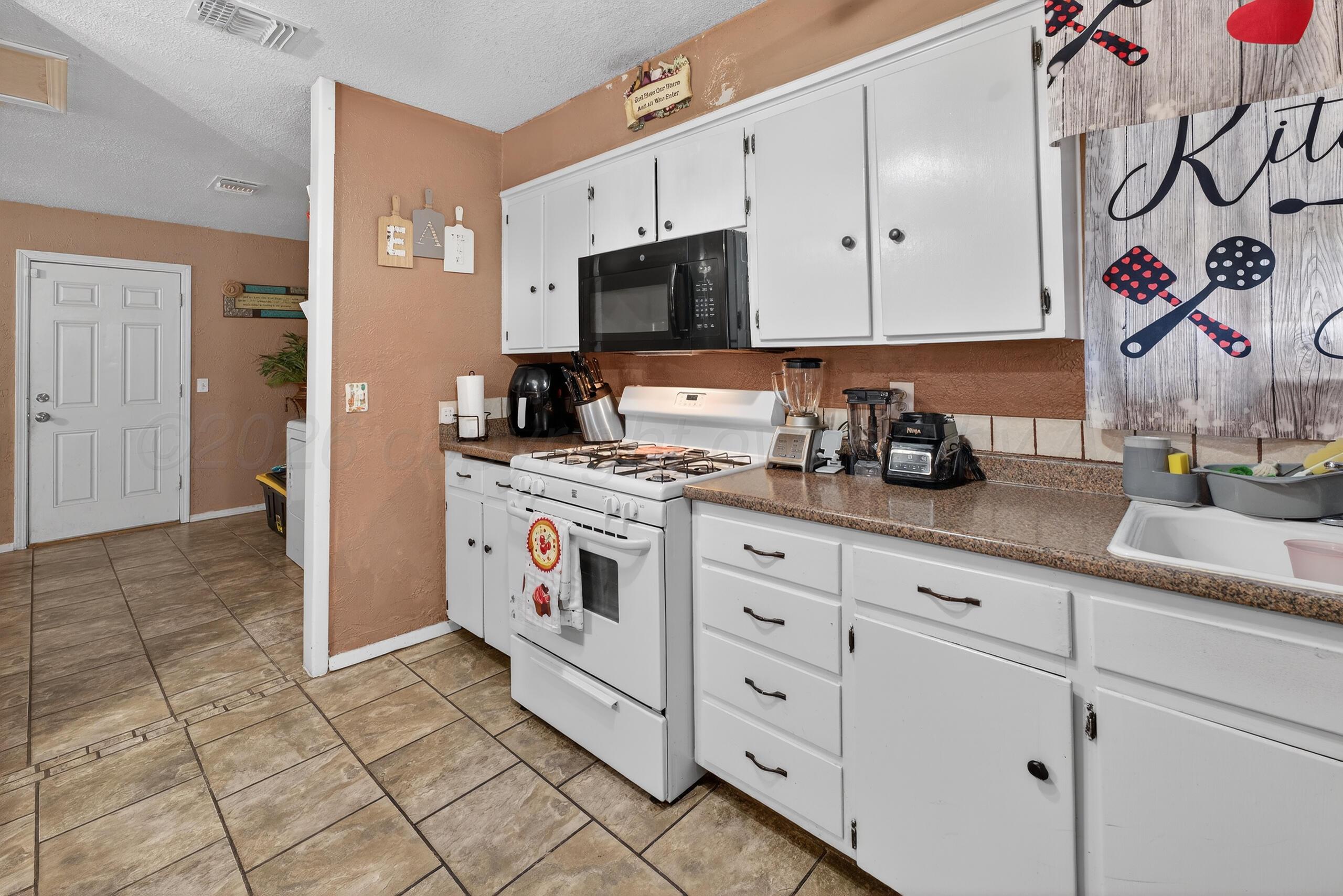 1007 Tudor Drive Amarillo, TX 79104 - Photo 8 of 27 a kitchen with stainless steel appliances white cabinets and a sink