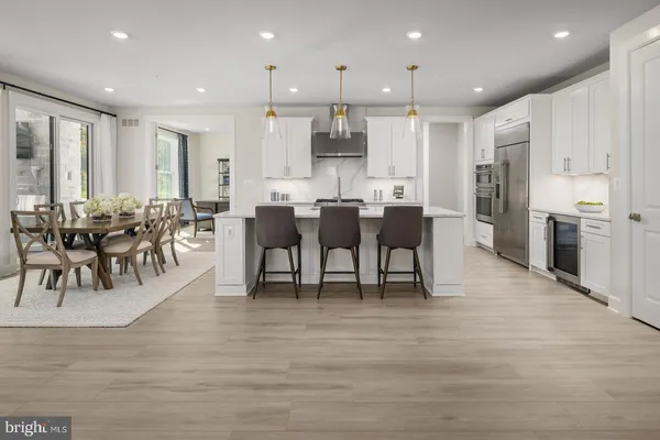 a view of a dining room and livingroom with furniture wooden floor a rug a fireplace and windows