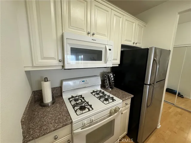a kitchen with granite countertop a refrigerator stove and sink
