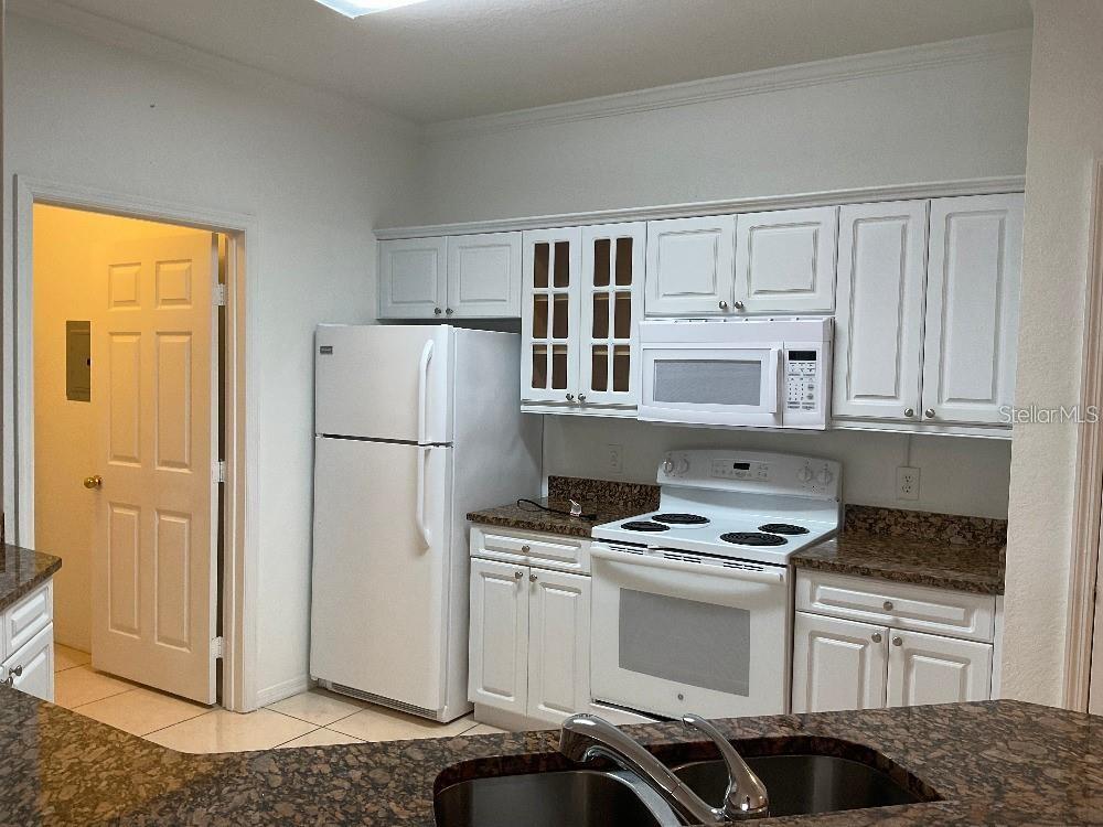 3701 Conroy Road, Unit 1822 Orlando, FL 32839 - Photo 4 of 23 a kitchen with granite countertop a refrigerator stove and white cabinets