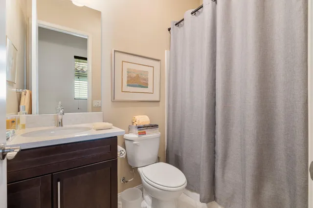 a bathroom with a sink a toilet a mirror and shower curtain