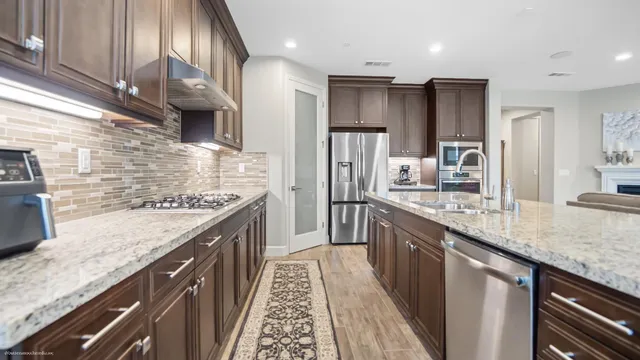 a kitchen with stainless steel appliances granite countertop wooden cabinets and a sink