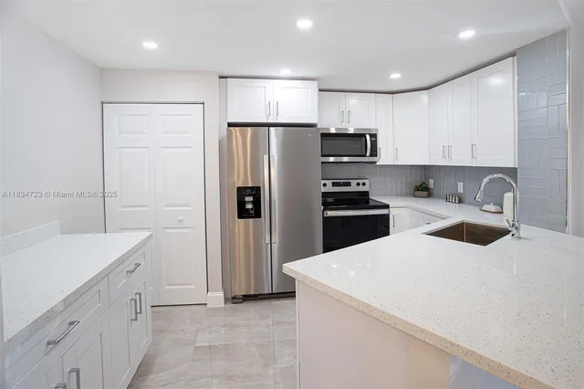 a kitchen with a sink a refrigerator and a stove top oven
