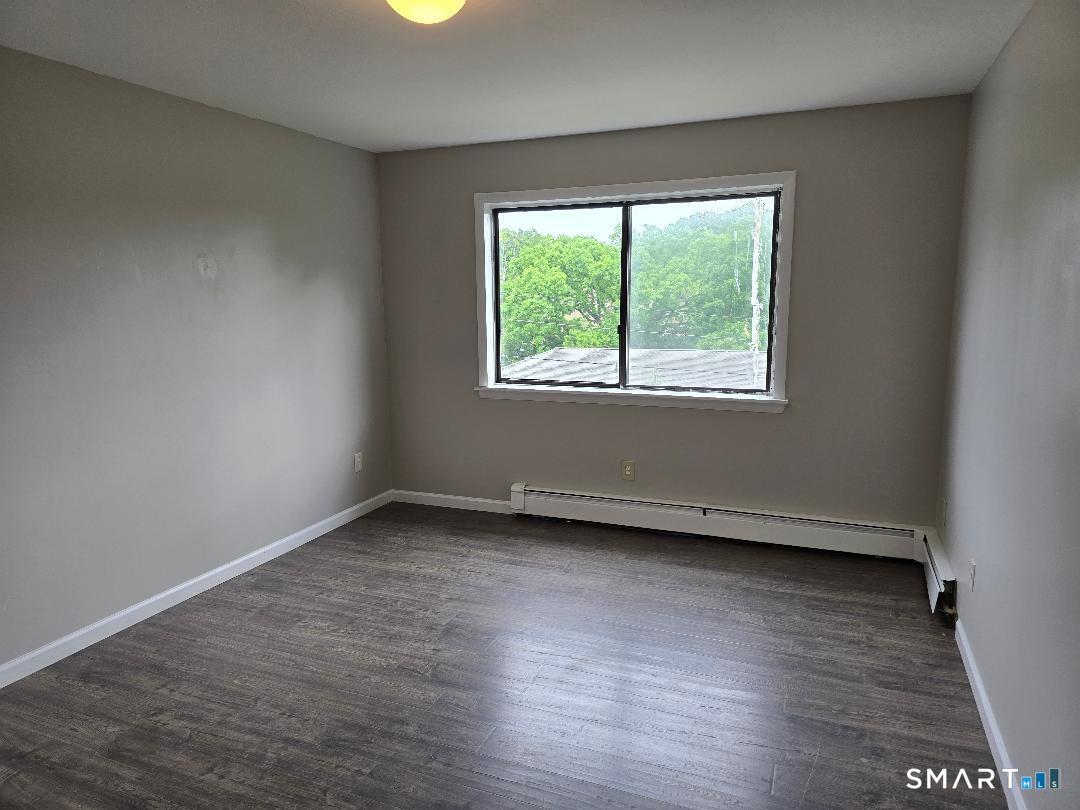 44 Armand Drive, Unit E Waterbury, CT 06708 - Photo 6 of 7 an empty room with wooden floor and windows