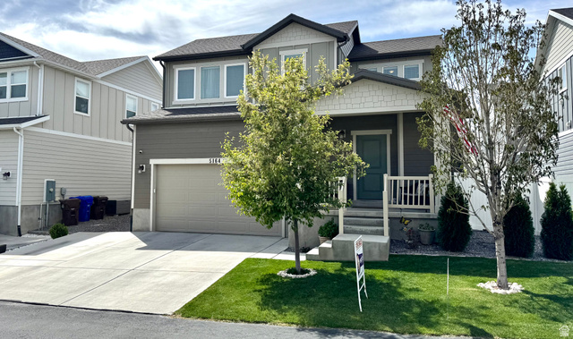 5164 East Rio Grande Way Eagle Mountain, UT 84005 - Photo 1 of 1 View of front facade with a garage, driveway, a porch, a front yard, and roof with shingles