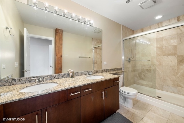 1040 West Adams Street, Unit 610 Chicago, IL 60607 - Photo 13 of 24 a bathroom with a granite countertop sink a toilet and shower