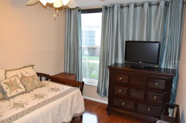 a bedroom with a bed and a flat tv screen on dresser