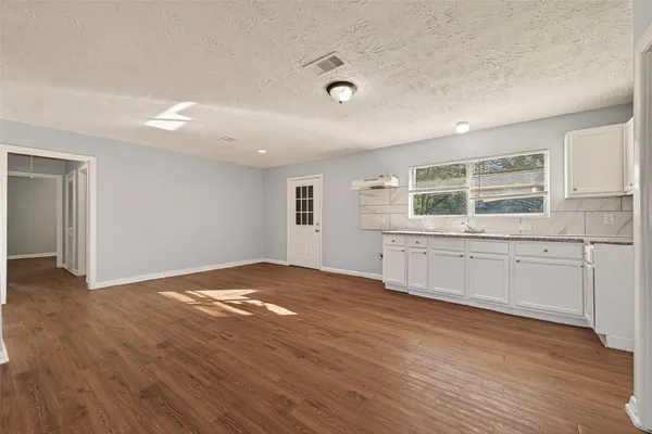 a view of an empty room with a window and wooden floor