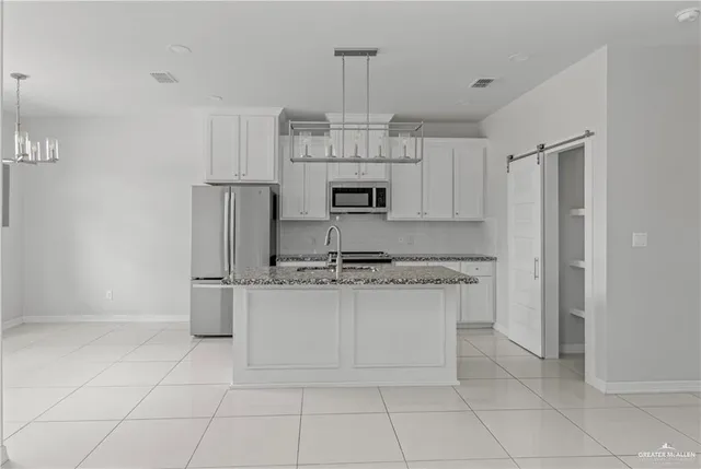 a kitchen with kitchen island granite countertop a stove a sink and a refrigerator