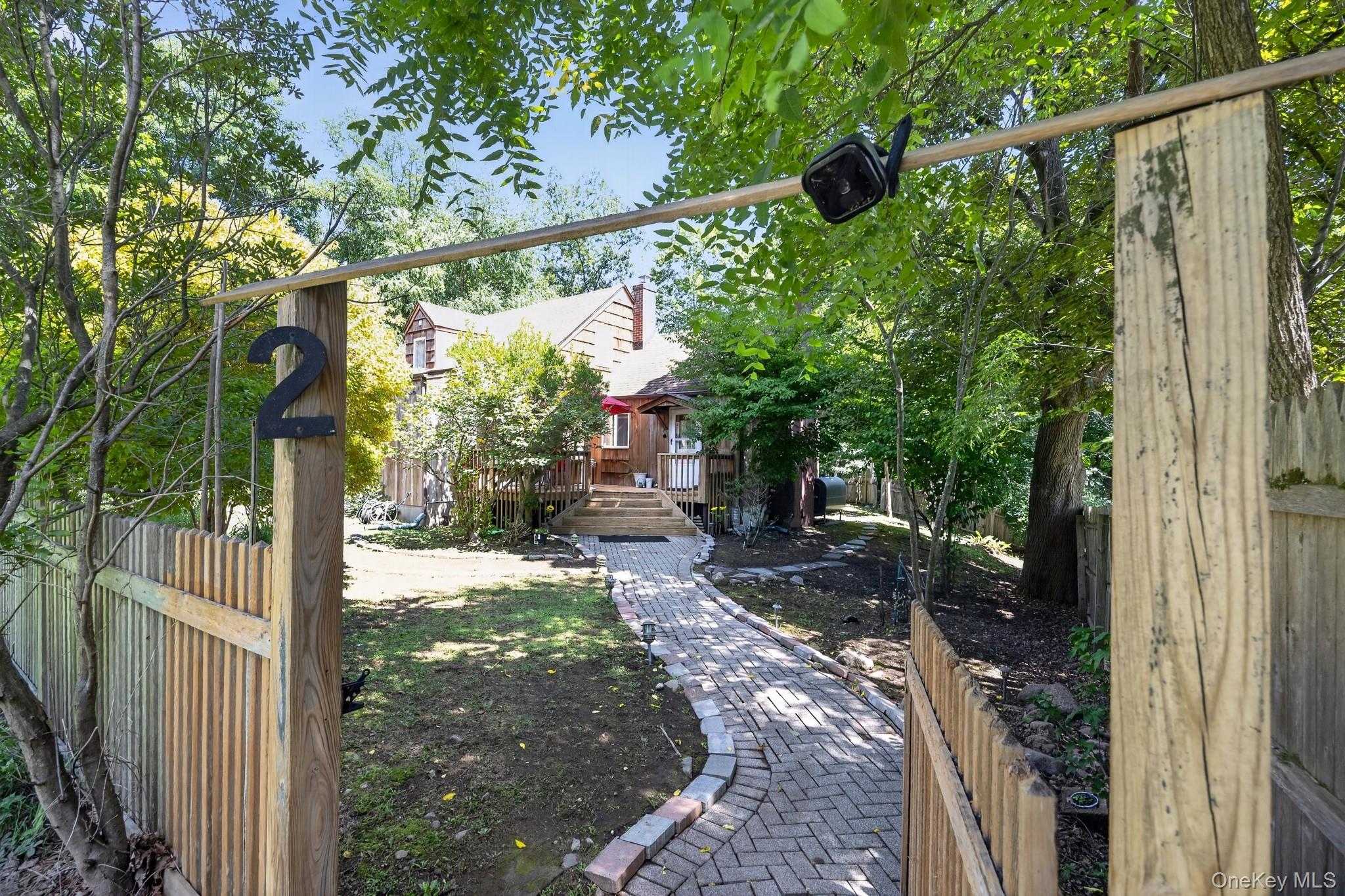2 Terrace Road Suffern, NY 10901 - Photo 11 of 19 Brick paver walkway leading to a wood-sided residence with an elevated wood deck