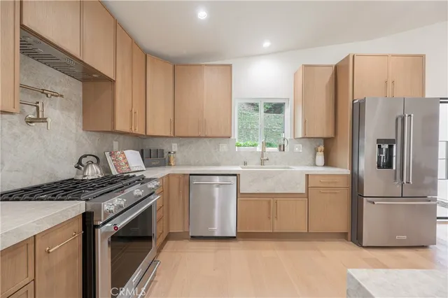 a kitchen with stainless steel appliances granite countertop a refrigerator sink and stove