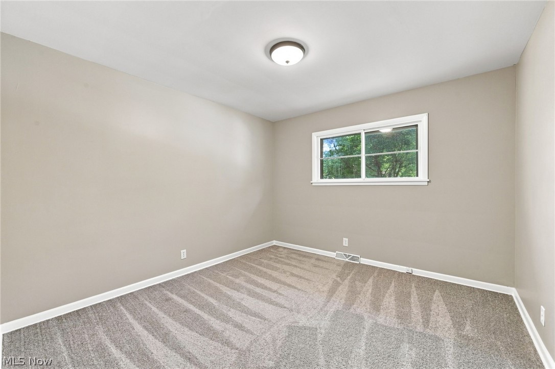 558 Garnette Road Akron, OH 44313 - Photo 17 of 31 Neutral-toned bedroom featuring a window with white trim, a flush-mount ceiling light, and carpet flooring