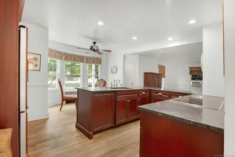 a kitchen with granite countertop a stove a sink a dining table and chairs