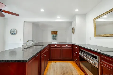 a kitchen with granite countertop a sink and a stove top oven with wooden floor