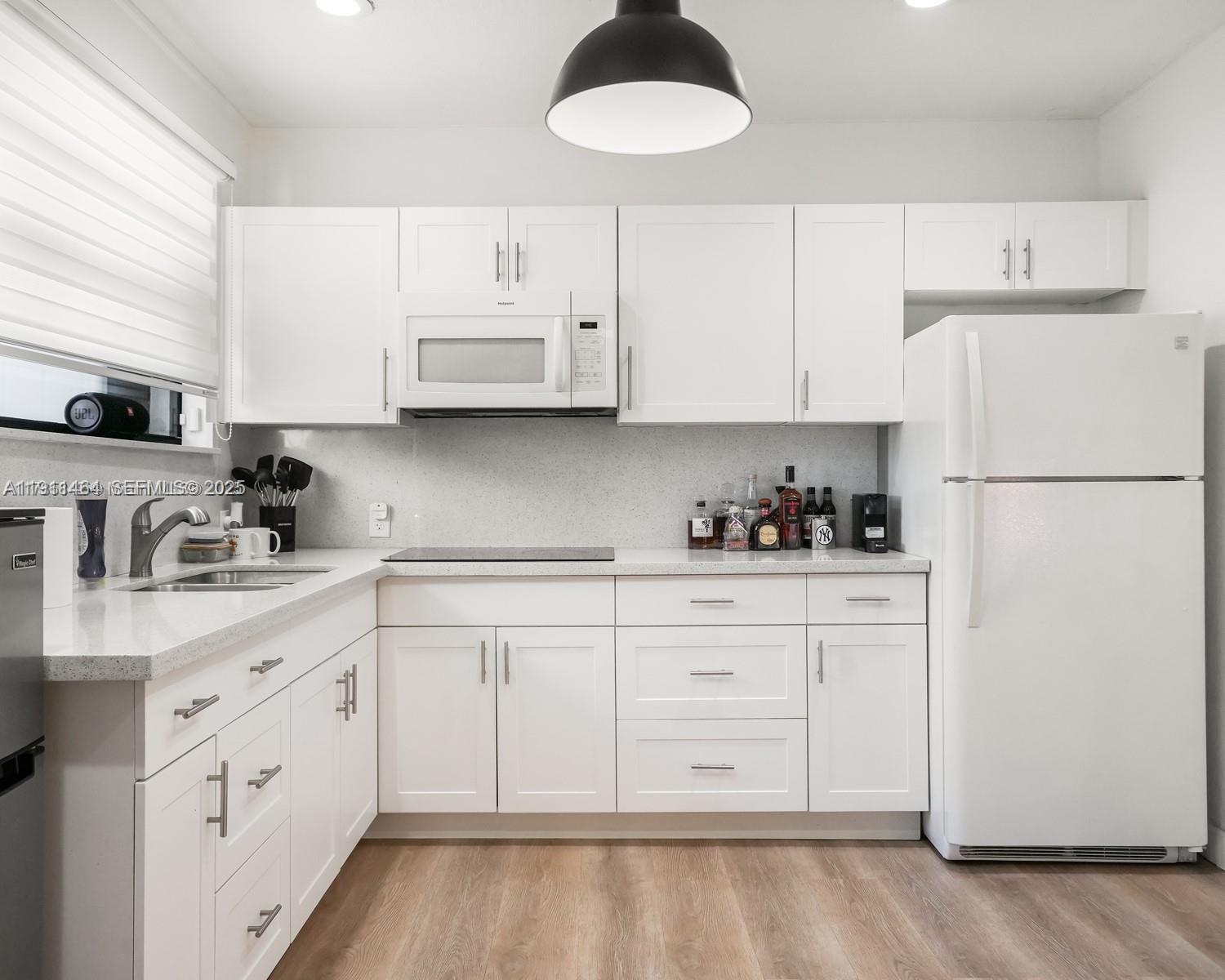 5629 Southwest 7th Street Miami, FL 33144 - Photo 16 of 22 a kitchen with granite countertop white cabinets and white appliances