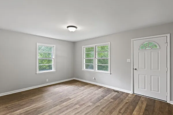 an empty room with wooden floor and windows