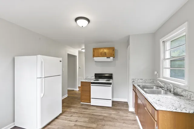 a kitchen with granite countertop a refrigerator stove and sink