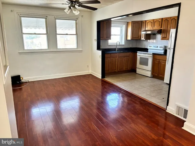 an empty room with wooden floor a sink and a window
