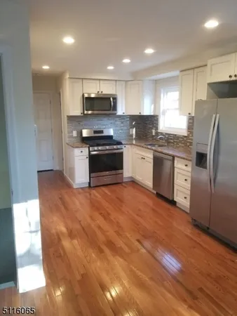 a large kitchen with stainless steel appliances granite countertop a stove a sink and a refrigerator