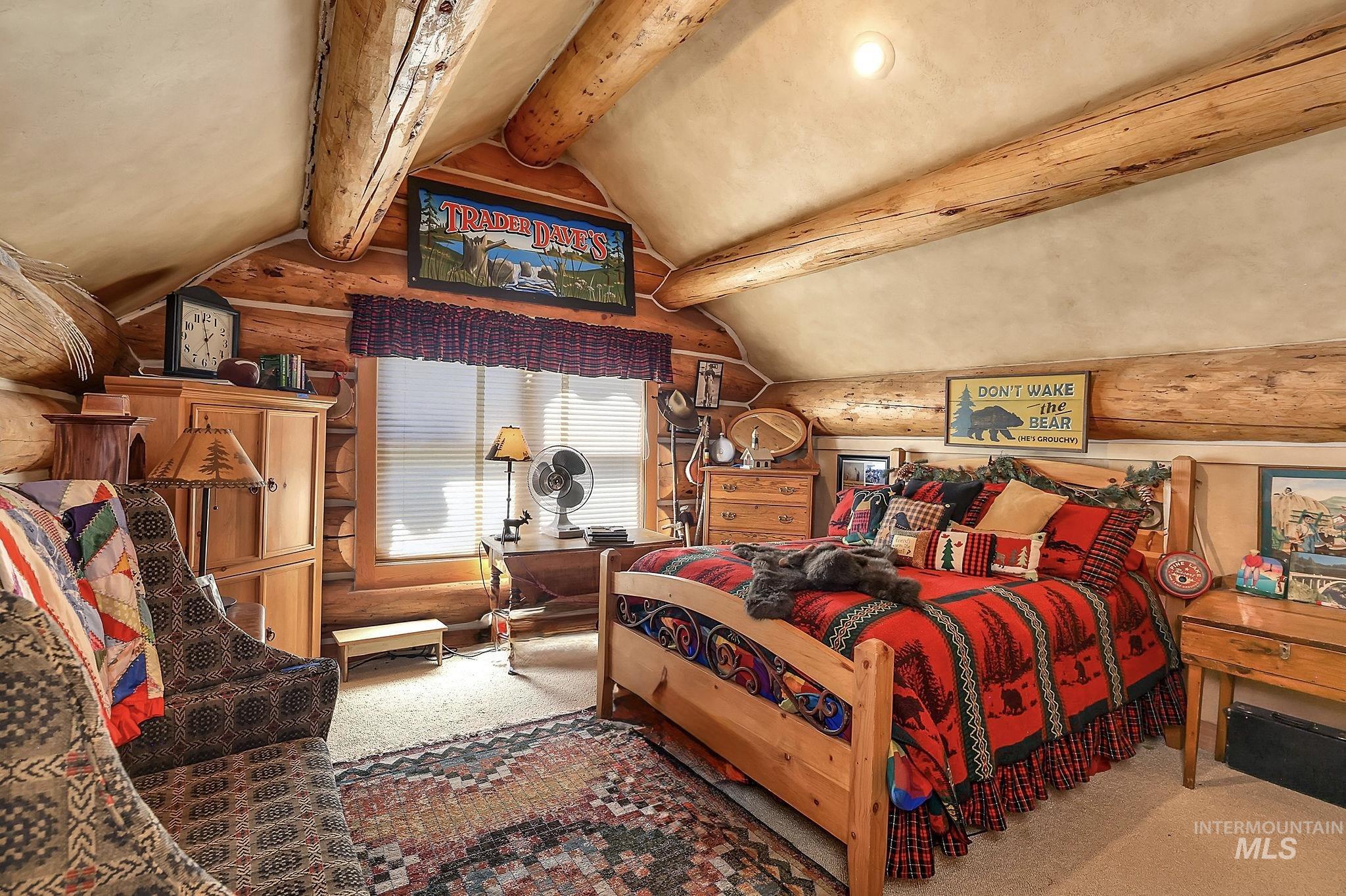 1345 Divot Lane McCall, ID 83638 - Photo 6 of 13 Log-paneled room featuring exposed log beams, a vaulted ceiling, and a prominent window with horizontal blinds
