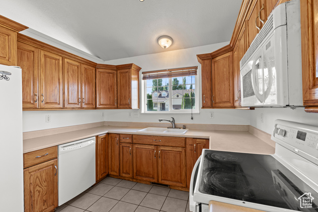 1099 Three Point Avenue Logan, UT 84321 - Photo 9 of 27 Kitchen with white appliances, lofted ceiling, brown cabinets, light tile patterned flooring, and light countertops