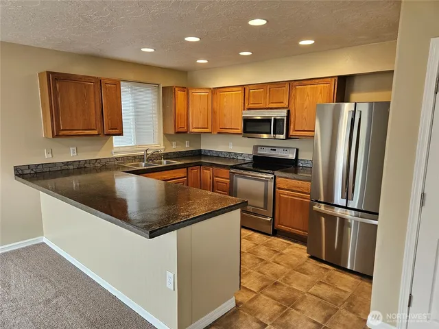 a kitchen with kitchen island granite countertop a sink stove and refrigerator